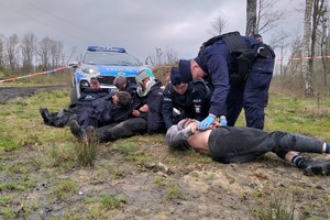 Zdjęcie przedstawia inscenizowaną sytuację pierwszej pomocy udzielanej przez policjantów osobom, które doznały obrażeń ciała na skutek zdarzenia o charakterze terrorystycznym.