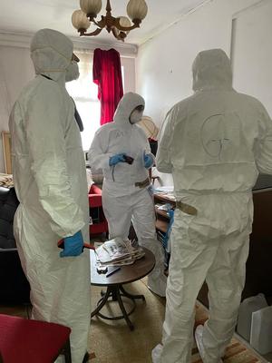 Zdjęcie przedstawia trzech uczestników szkolenia wykonujących zadanie ćwiczebne, ubranych w kombinezony ochronne.