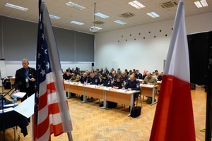 Zdjęcie uczestników szkolenia z flagami Polski i USA w tle.