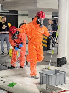 Zdjęcie przedstawia  funkcjonariuszy wykonujących ćwiczebne czynności na miejscu zdarzenia- wystąpienia zagrożenia CBRNE.