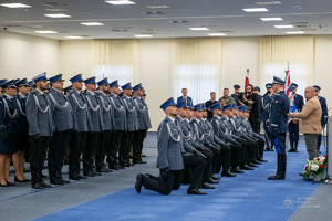 Komendant Główny Policji nadinsp. Marek Boroń mianuje policjantów na pierwszy stopień oficerski przykładając im szable do ramienia