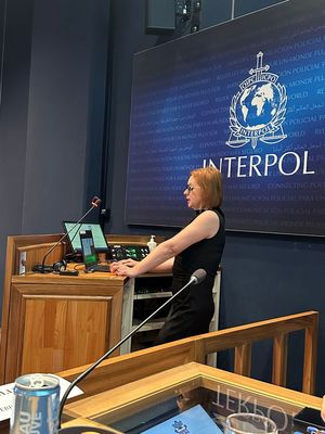 podinsp. Magdalena Jabłońska - Milczarek z Centralnego Laboratorium Kryminalistycznego Policji stoi przy mównicy i prowadzi wykład i warsztaty.