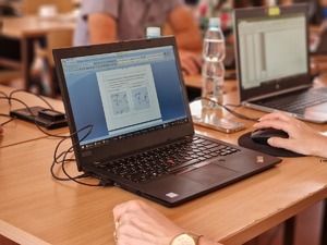 Zdjęcie przedstawia laptopa oraz grafikę znajdującą się na pulpicie porównującą podpis biometryczny.