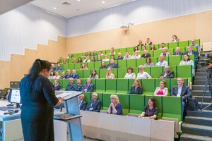 Zdjęcie przedstawia konferencję w auli oraz osobę prowadzącą wykład i osoby siedzące które uczestniczyły w prelekcji, której tematem przewodnim były innowacje i wyzwania w chemii kryminalistycznej.