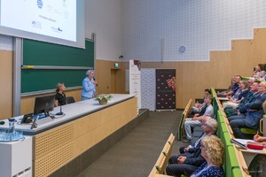 Zdjęcie przedstawia konferencję w auli oraz osoby prowadzące wykład i osoby siedzące, które uczestniczyły w prelekcji, której tematem przewodnim były innowacje i wyzwania w chemii kryminalistycznej.