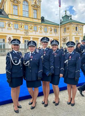 Podczas obchodów Święta Policji na tle zamku w Wilanowie stoją obok siebie policjantki ubrane w mundury galowe. Pozują do zdjęcia wraz z Dyrektor Centralnego Laboratorium Kryminalistycznego Policji insp. Iwoną Marcianiak - Krawczyk.