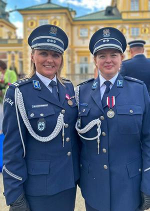Podczas obchodów Święta Policji na tle zamku w Wilanowie stoją obok siebie  Dyrektor Centralnego Laboratorium Kryminalistycznego Policji insp. Iwoną Marcianiak - Krawczyk oraz podkom. Emilia Liwarowska biegła Centralnego laboratorium Kryminalistycznego Policji.i pozują do zdjęcia.