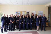 Policjanci ubrani w mundury ćwiczebne pozują do wspólnego zdjęcia stojąc jeden obok drugiego .