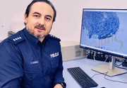 Zdjęcie przedstawia Aktora Zbigniewa Kozłowskiego w mundurze policyjnym siedzącego przy monitorze komputera.